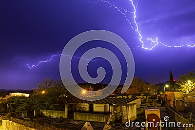 Lightning cracking during thunderstorm over houses of tiny town Stock Photo